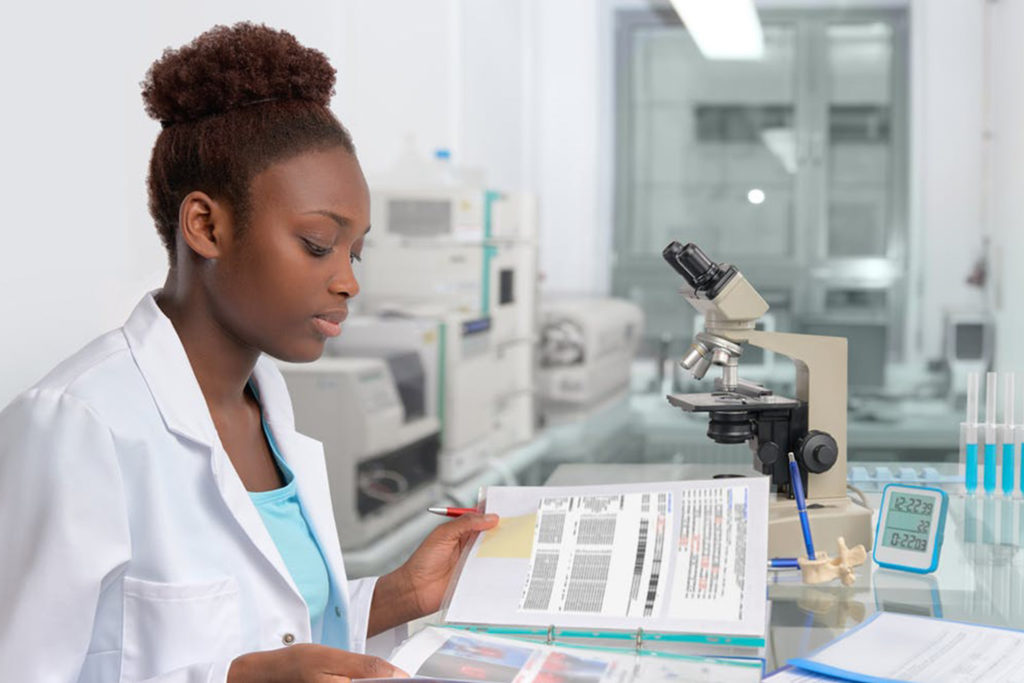 A woman in a medical lab looking through a booklet of documents