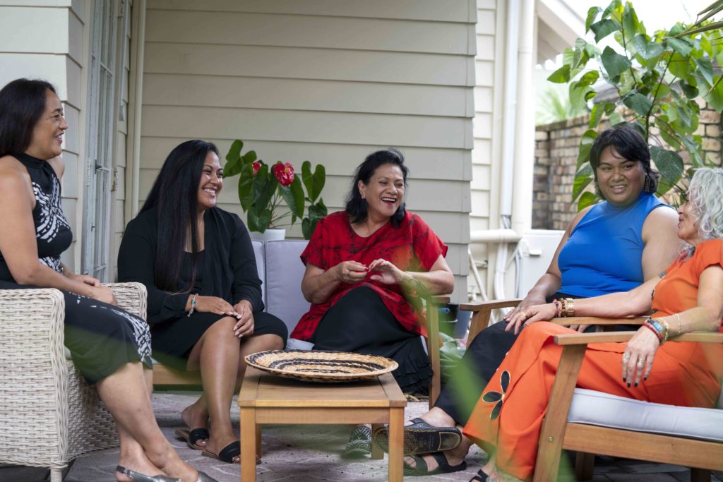 a group of women sitting on a patio, laughing and conversing