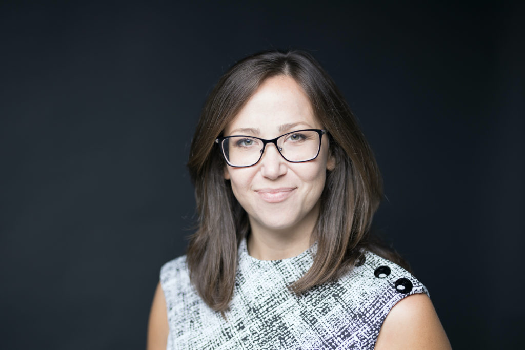 This is a photo of Libi Berenson wearing a black and white shirt and glasses. 