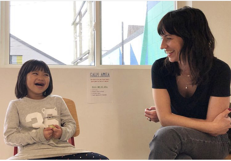 A team member at The Writers' Exchange laughing with a young child