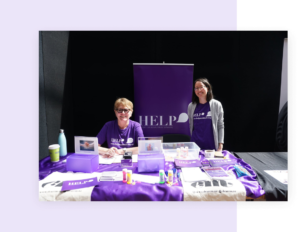 this is a photo of two women in purple at a booth for survivors of abuse